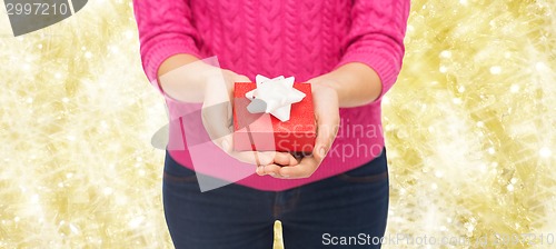 Image of close up of woman in pink sweater holding gift box