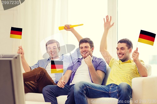 Image of happy male friends with flags and vuvuzela