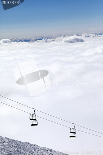 Image of Ski slope, chair-lift and mountains under clouds