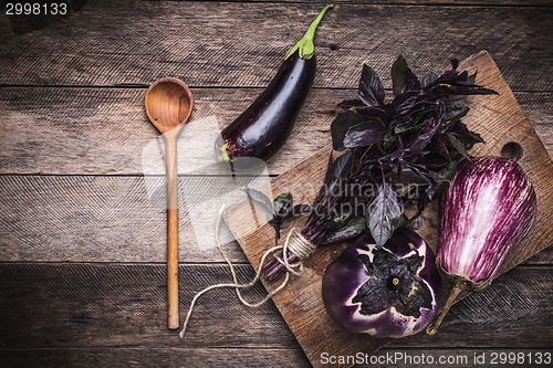 Image of Aubergines, basil and spoon on wooden table