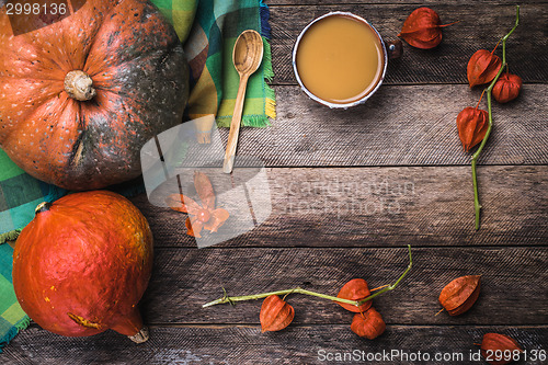 Image of Rustic style pumpkins, soup and ground cherry branches on wood