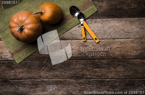 Image of Two pumpkins with spoons on green napkin and wood in Rustic styl