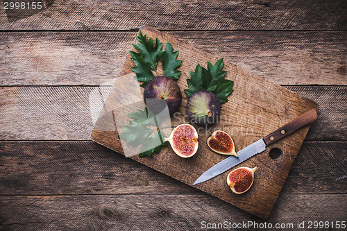 Image of rustic style Cut figs with knife on chopping board and wooden ta