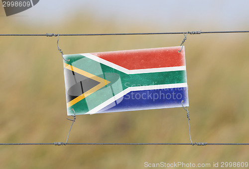 Image of Border fence - Old plastic sign with a flag