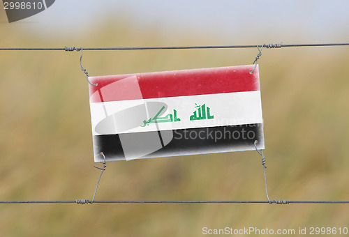 Image of Border fence - Old plastic sign with a flag