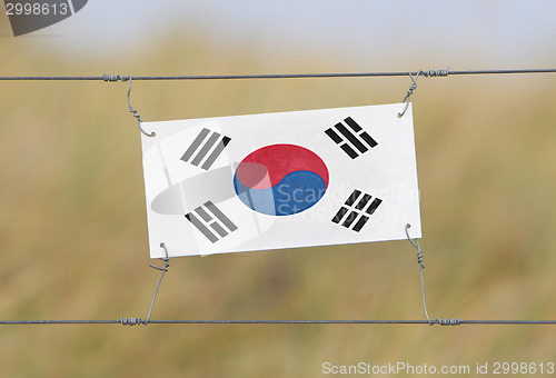 Image of Border fence - Old plastic sign with a flag