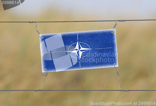 Image of Border fence - Old plastic sign with a flag