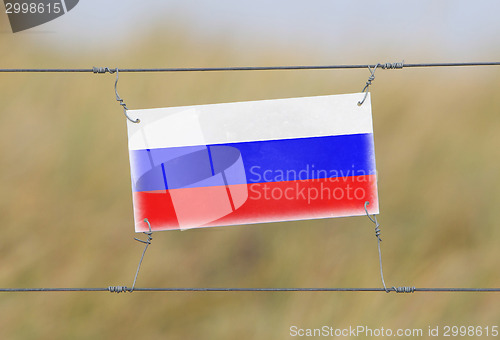 Image of Border fence - Old plastic sign with a flag