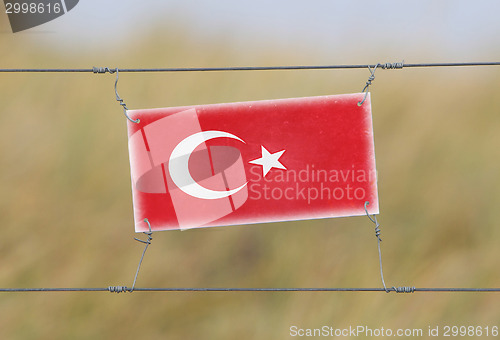 Image of Border fence - Old plastic sign with a flag