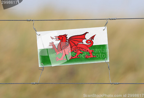 Image of Border fence - Old plastic sign with a flag