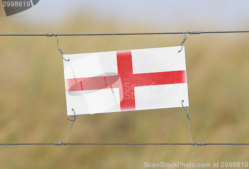 Image of Border fence - Old plastic sign with a flag