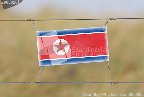 Image of Border fence - Old plastic sign with a flag