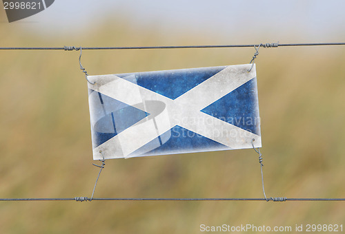 Image of Border fence - Old plastic sign with a flag