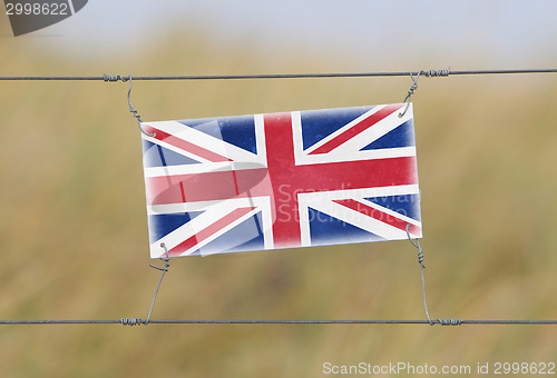 Image of Border fence - Old plastic sign with a flag