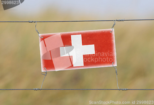 Image of Border fence - Old plastic sign with a flag