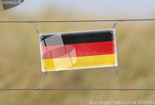 Image of Border fence - Old plastic sign with a flag