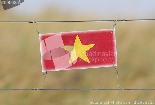 Image of Border fence - Old plastic sign with a flag