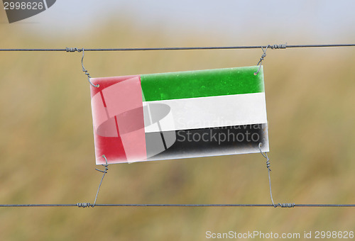 Image of Border fence - Old plastic sign with a flag