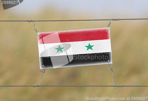 Image of Border fence - Old plastic sign with a flag