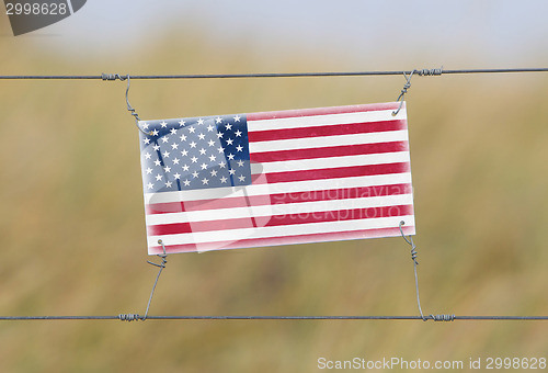 Image of Border fence - Old plastic sign with a flag