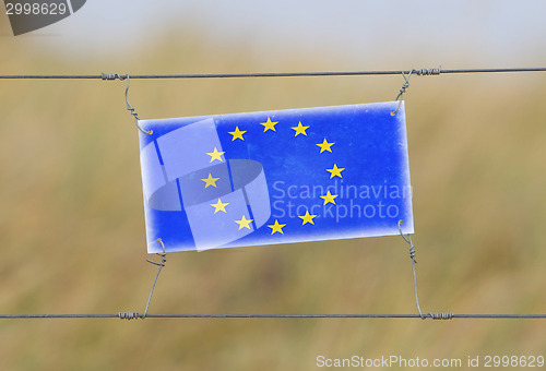 Image of Border fence - Old plastic sign with a flag