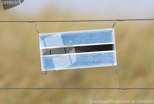 Image of Border fence - Old plastic sign with a flag