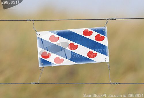 Image of Border fence - Old plastic sign with a flag