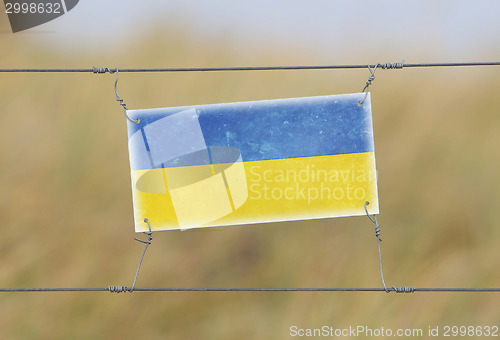 Image of Border fence - Old plastic sign with a flag