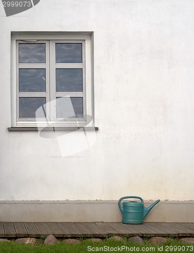 Image of plastic watering can near the white wall