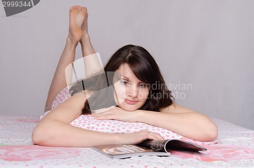 Image of Girl infatuated interesting article while lying in bed