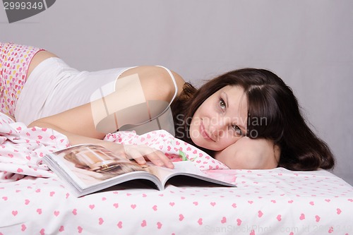 Image of Beautiful girl relaxed in bed with magazine