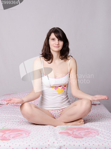 Image of Woman meditating sitting on the bed