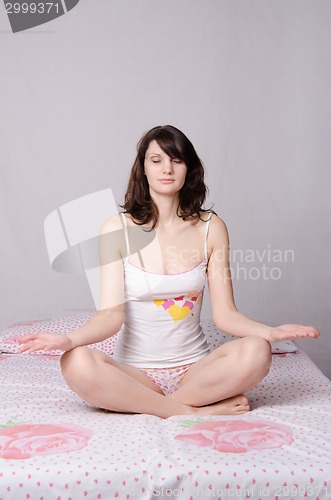 Image of Woman meditating sitting on bed