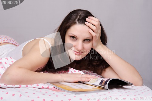 Image of Beautiful girl with a magazine in bed