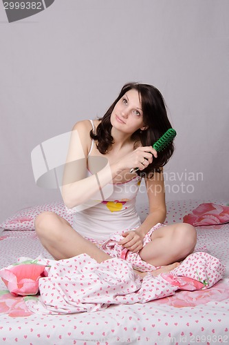 Image of Positive girl waking up brushing her hair