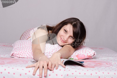 Image of Happy girl with a magazine in bed