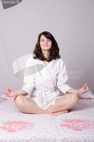 Image of Woman meditating sitting on the bed