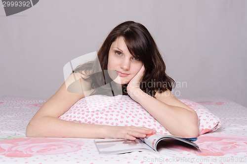 Image of Beautiful girl reading a magazine wondered in bed