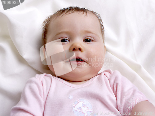 Image of Baby girl lying on a blanket looking into the camera