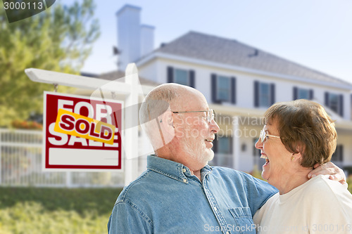 Image of Senior Couple in Front of Sold Real Estate Sign, House