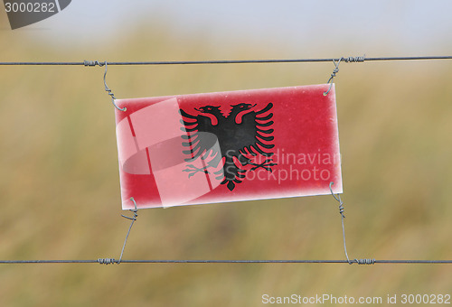 Image of Border fence - Old plastic sign with a flag