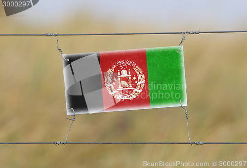 Image of Border fence - Old plastic sign with a flag