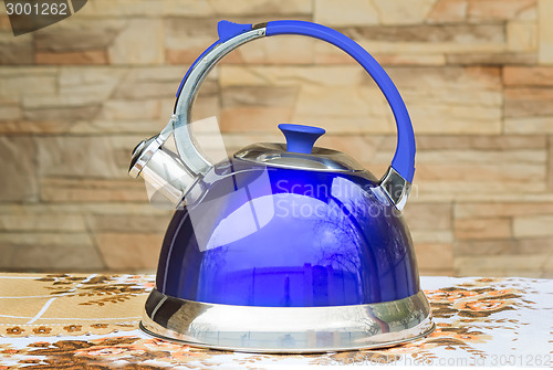 Image of Bright blue kettle on the tablecloth table.