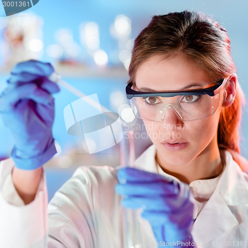 Image of Attractive young scientist pipetting.
