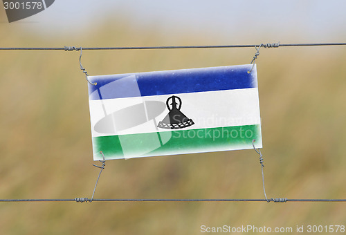 Image of Border fence - Old plastic sign with a flag