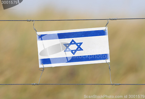 Image of Border fence - Old plastic sign with a flag