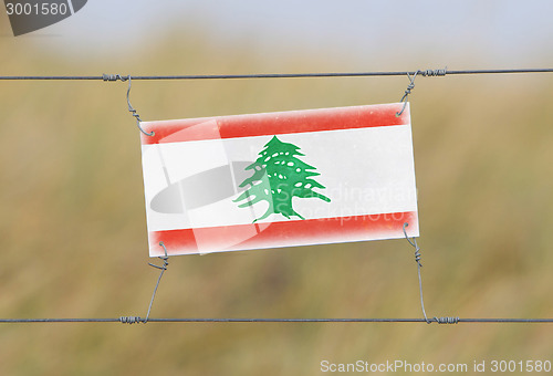 Image of Border fence - Old plastic sign with a flag