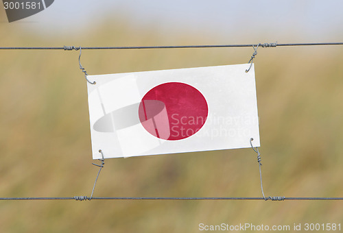 Image of Border fence - Old plastic sign with a flag