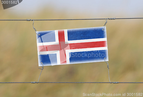 Image of Border fence - Old plastic sign with a flag