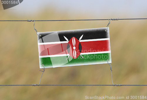 Image of Border fence - Old plastic sign with a flag